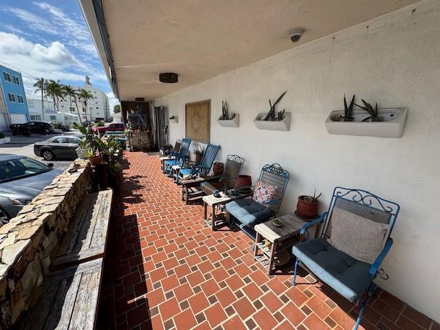 A covered outdoor patio features a red tiled floor, multiple chairs, and wall-mounted planters — 308 Monroe Street, Hollywood FL 33019, HOLLYWOOD, FL