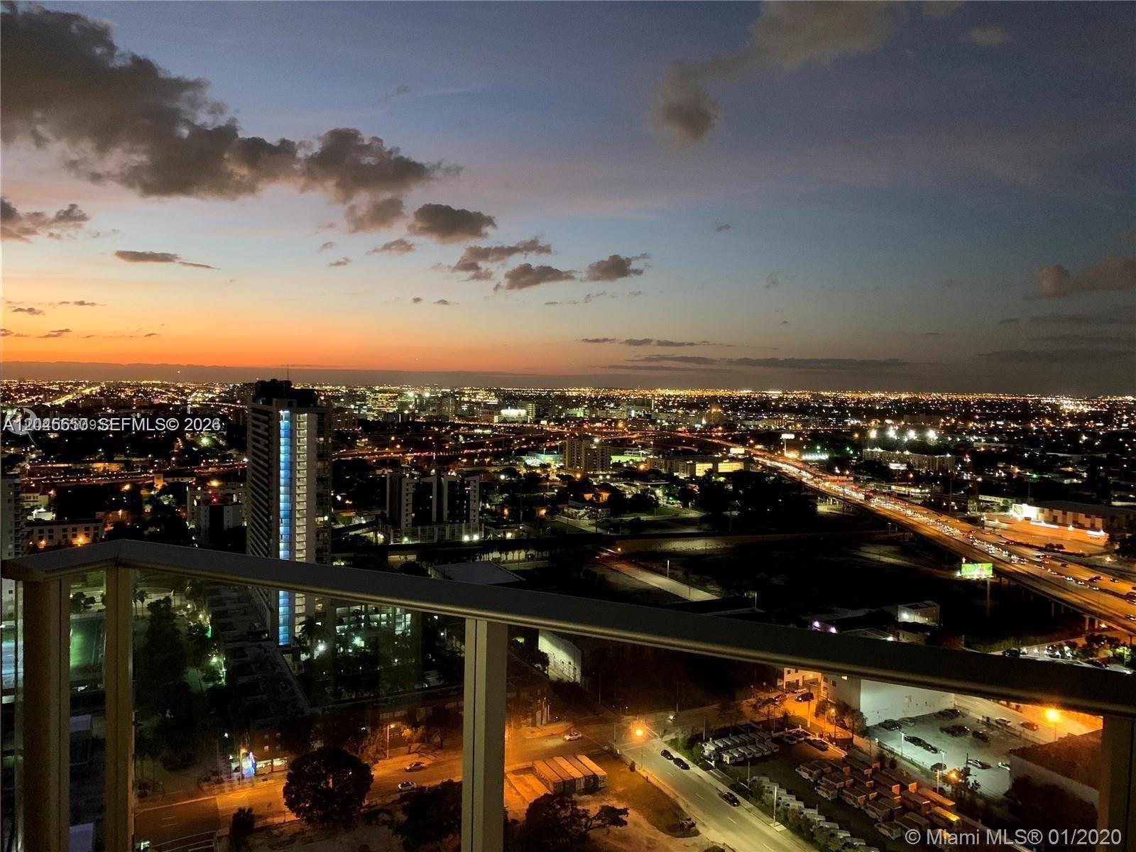 A high-angle view from a balcony overlooks a city skyline at sunset — 851 NE 1st Ave # 2702, Miami FL 33132, MIAMI, FL