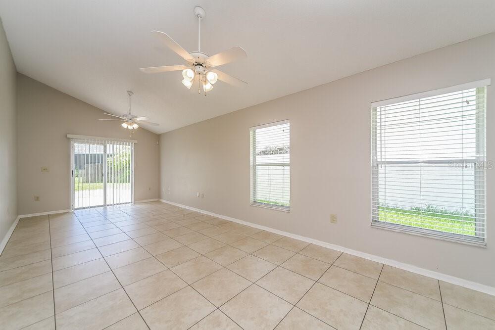 An empty room with beige tile flooring, two ceiling fans, and sliding glass doors — 11904 ATLIN DRIVE, ORLANDO, FL