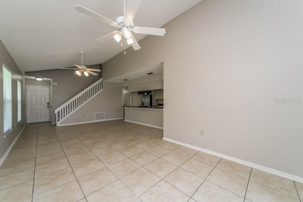 An open living area features tile flooring, a vaulted ceiling, and a staircase — 11904 ATLIN DRIVE, ORLANDO, FL