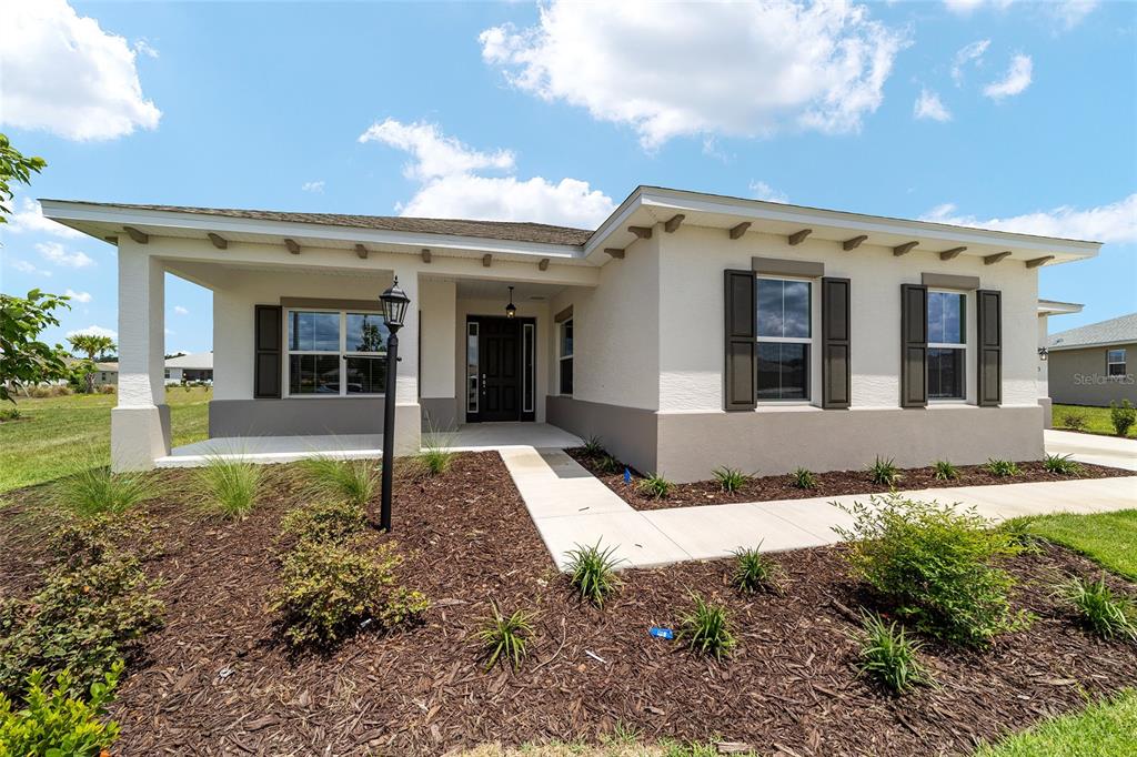 A single-story house with a covered front porch, stucco exterior, and dark shutters — 10673 SW 102ND LANE, OCALA, FL