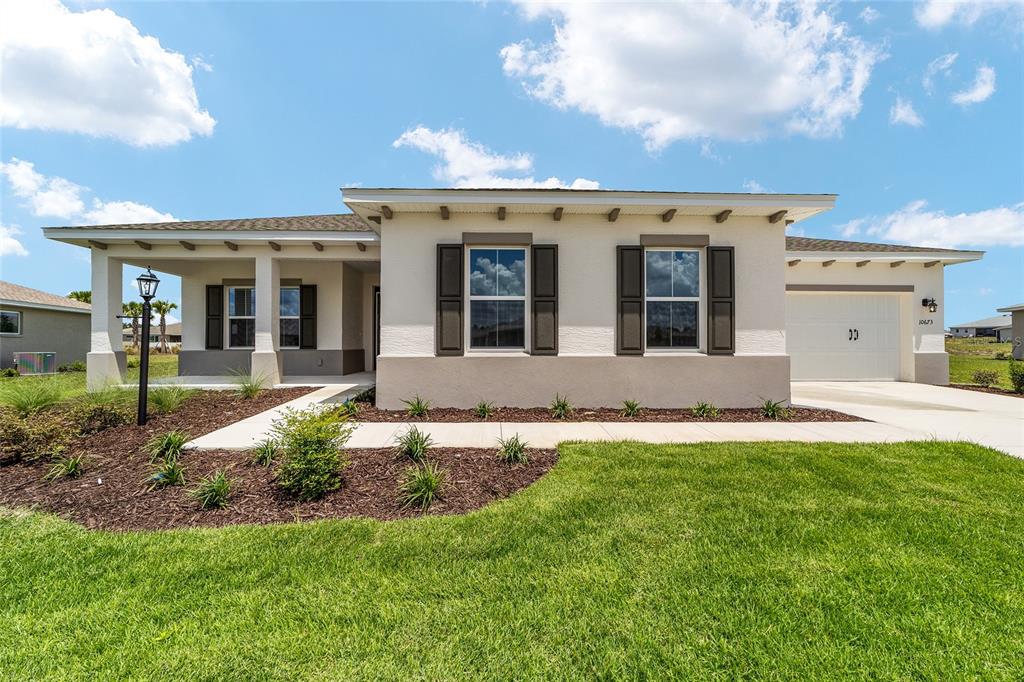 A single-story house with a white stucco facade, dark shutters, and a two-car garage — 10673 SW 102ND LANE, OCALA, FL