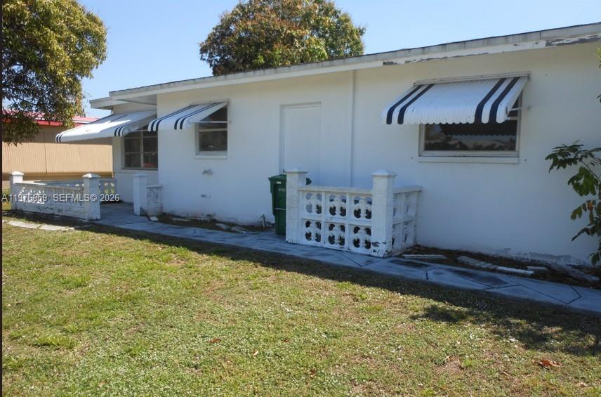 The exterior of a white, single-story house features striped window awnings and concrete block railings — 4955 NW 55th St, Tamarac FL 33319, TAMARAC, FL