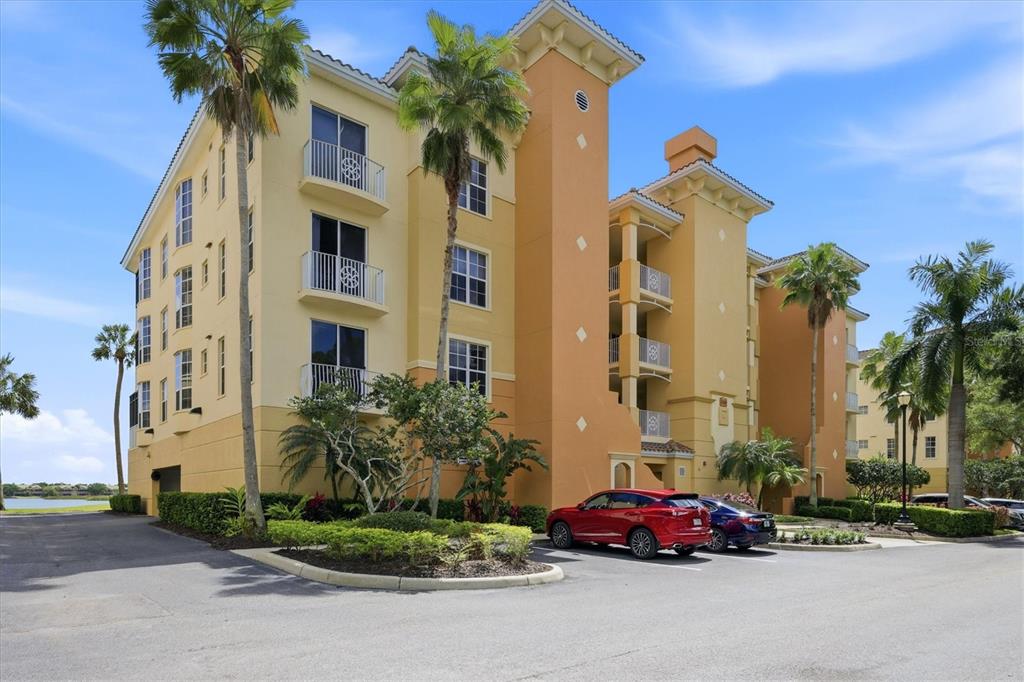 A multi-story yellow apartment building with balconies and a parking lot in the foreground — 6360 WATERCREST WAY UNIT 201, LAKEWOOD RANCH, FL