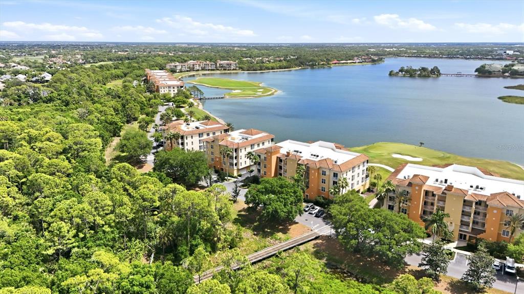 An aerial view shows multi-story apartment buildings situated along a lake and golf course — 6360 WATERCREST WAY UNIT 201, LAKEWOOD RANCH, FL