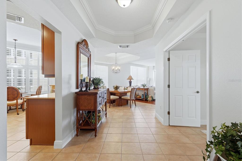 A tiled hallway leads to a dining area and living room with tray ceilings — 6360 WATERCREST WAY UNIT 201, LAKEWOOD RANCH, FL