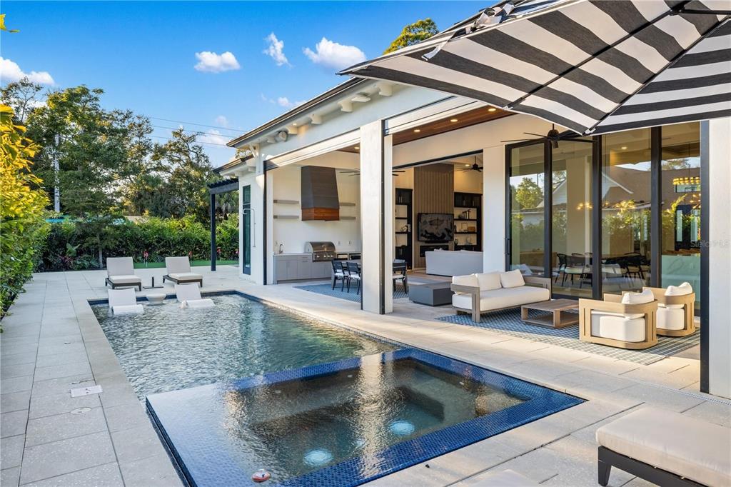 A modern outdoor patio features a swimming pool, hot tub, and covered lounge area — 1800 WEBBER STREET, SARASOTA, FL