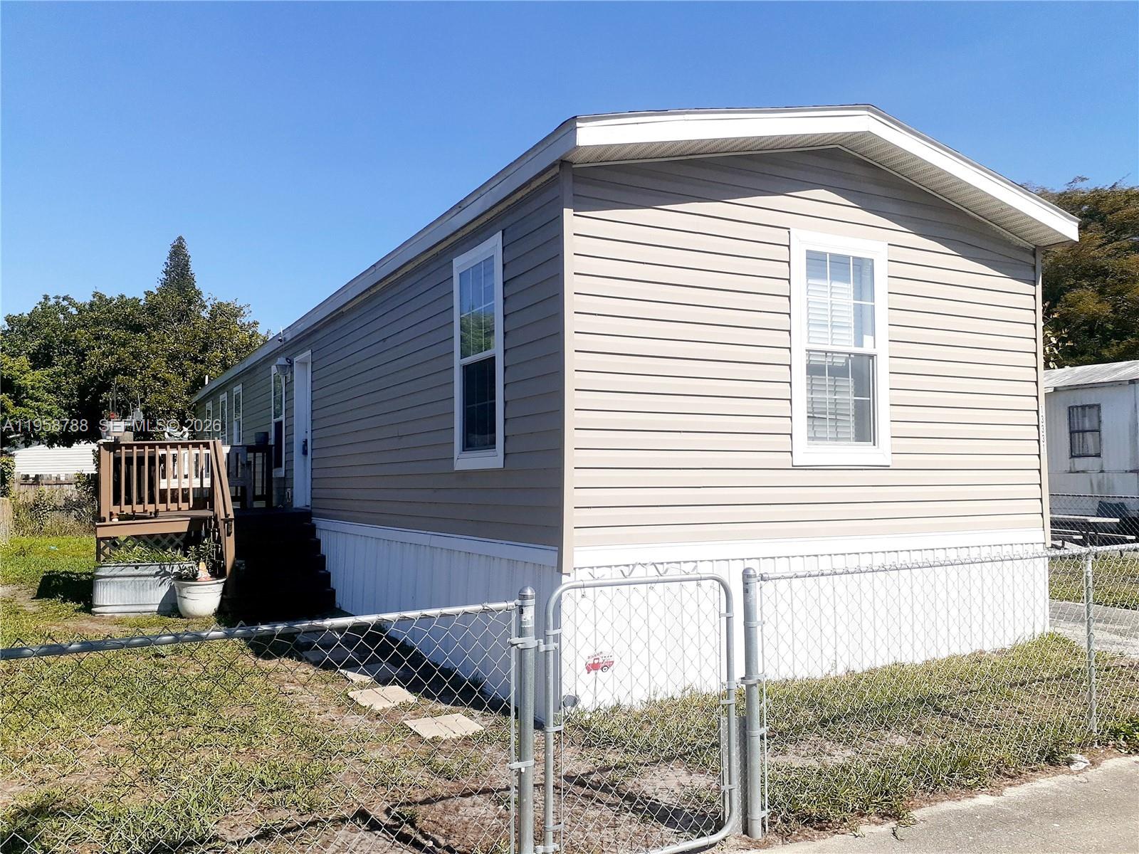 A single-story manufactured home with light-colored siding and a small wooden deck — 13331 SW 7th Pl, Davie FL 33325, DAVIE, FL