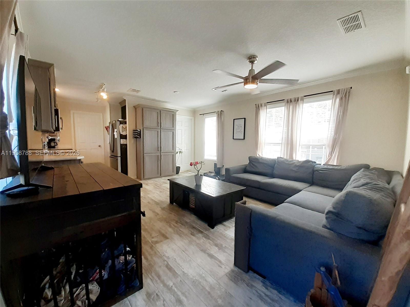 A living room features a gray sectional sofa, a dark coffee table, and wood-look flooring — 13331 SW 7th Pl, Davie FL 33325, DAVIE, FL