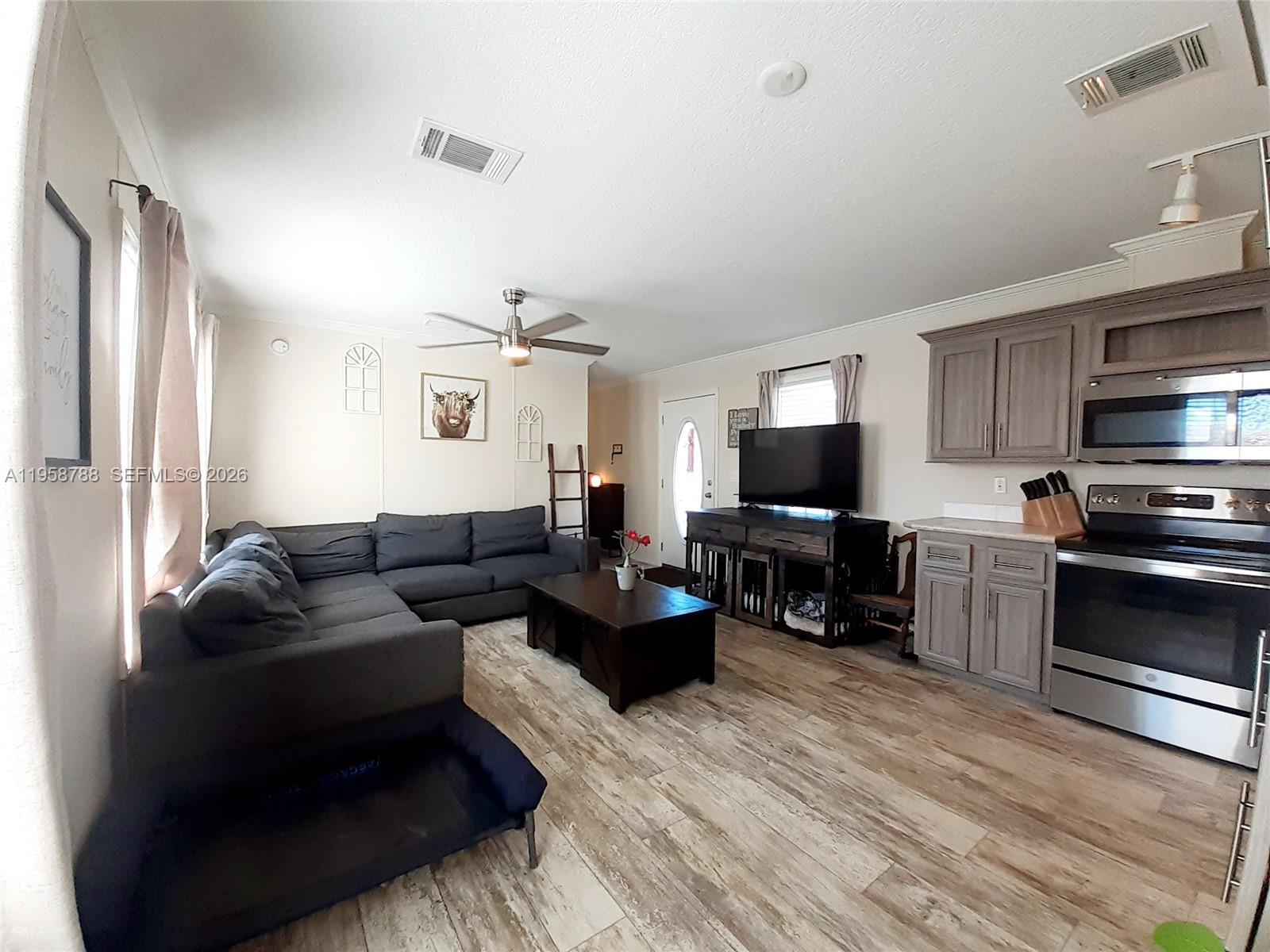 A living room features a gray sectional sofa, a coffee table, and an adjacent kitchen — 13331 SW 7th Pl, Davie FL 33325, DAVIE, FL