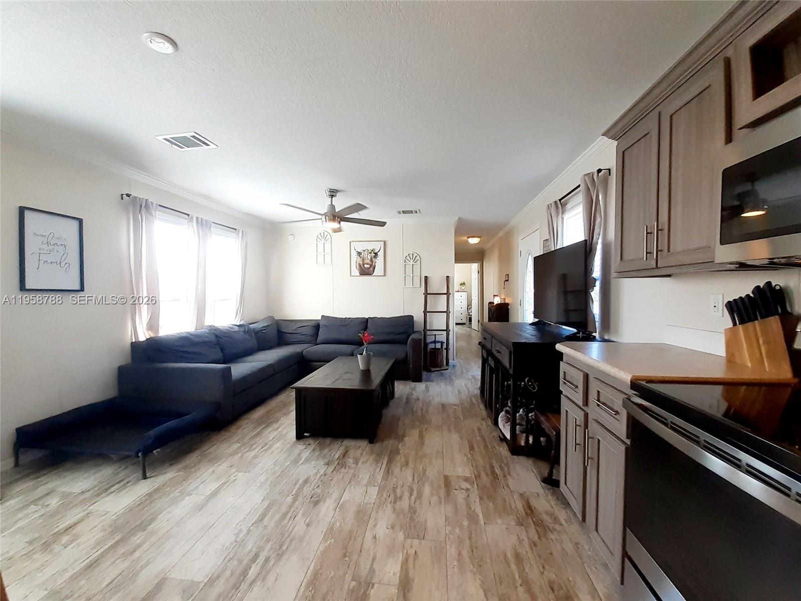 An open-concept living room and kitchen feature wood-look flooring, a large sectional, and cabinetry — 13331 SW 7th Pl, Davie FL 33325, DAVIE, FL