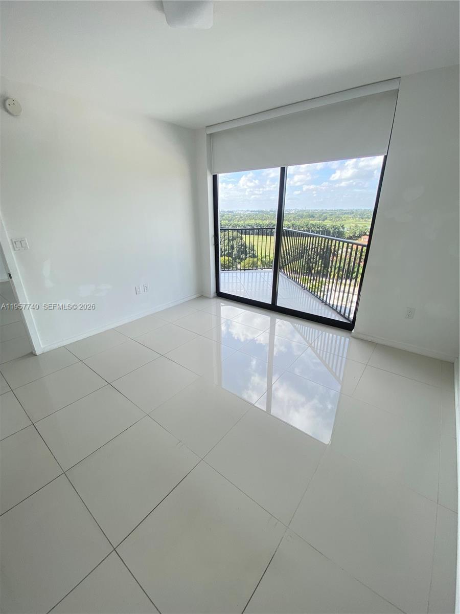 An empty room with white walls, large glossy floor tiles, and a balcony with views — 5252 NW 85th Ave # 910, Doral FL 33166, DORAL, FL