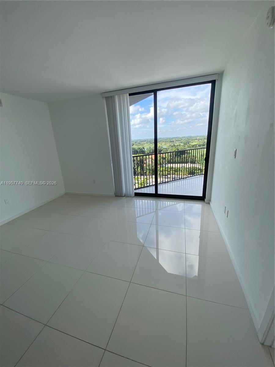 An empty room with white tile floors and a sliding glass door leading to a balcony — 5252 NW 85th Ave # 910, Doral FL 33166, DORAL, FL