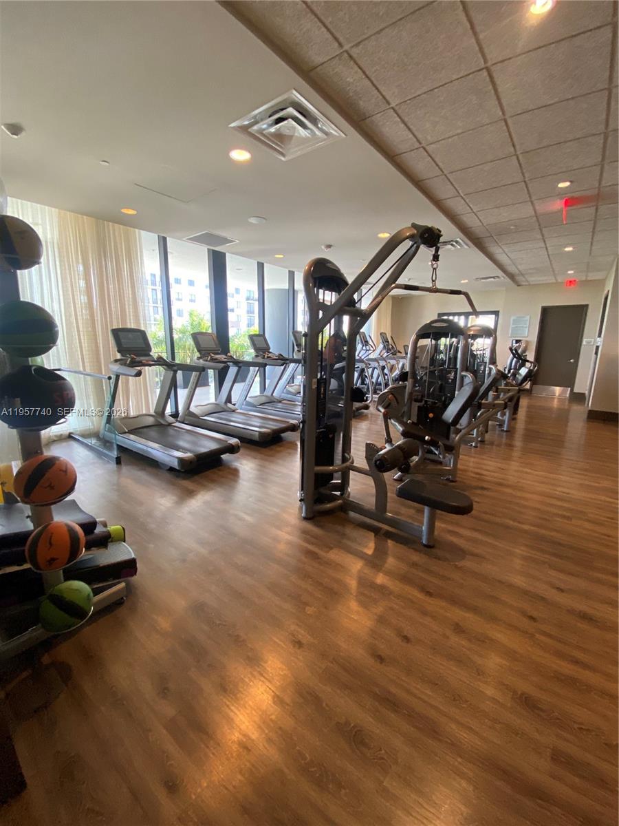 This gym features wood-look flooring, multiple treadmills, a weight machine, and a medicine ball rack — 5252 NW 85th Ave # 910, Doral FL 33166, DORAL, FL