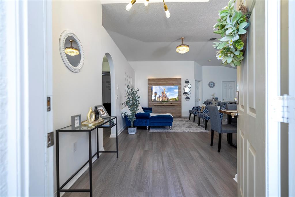 An entryway opens into a living room with wood-look flooring, a blue sofa, and dining area — 50989 HIGHWAY 27 UNIT 274, DAVENPORT, FL