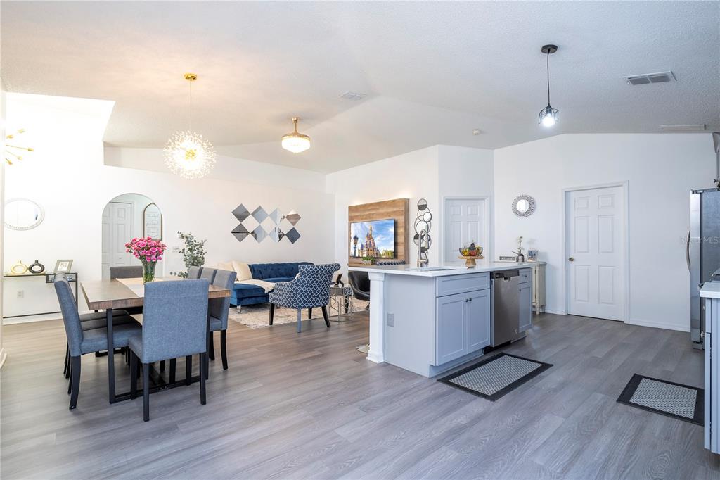 An open-concept living and dining area features light wood flooring, a kitchen island, and furniture — 50989 HIGHWAY 27 UNIT 274, DAVENPORT, FL