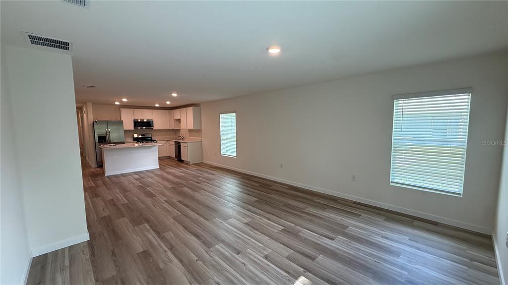 An open-concept living area features light wood-look flooring and a kitchen with white cabinetry — 7749 SW 46TH COURT, OCALA, FL