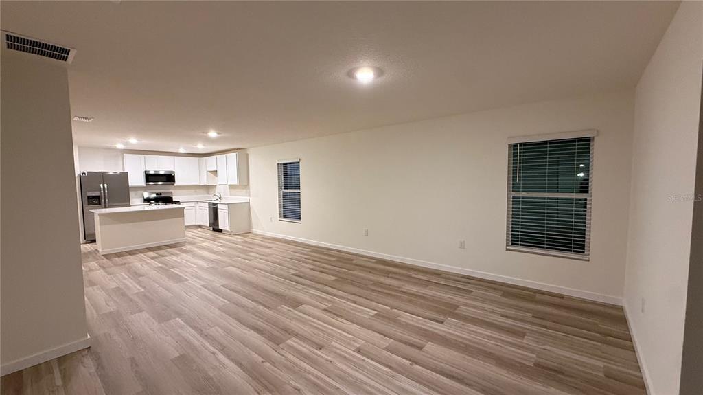 An open-concept living area features light wood-look flooring and a kitchen with white cabinetry — 7749 SW 46TH COURT, OCALA, FL
