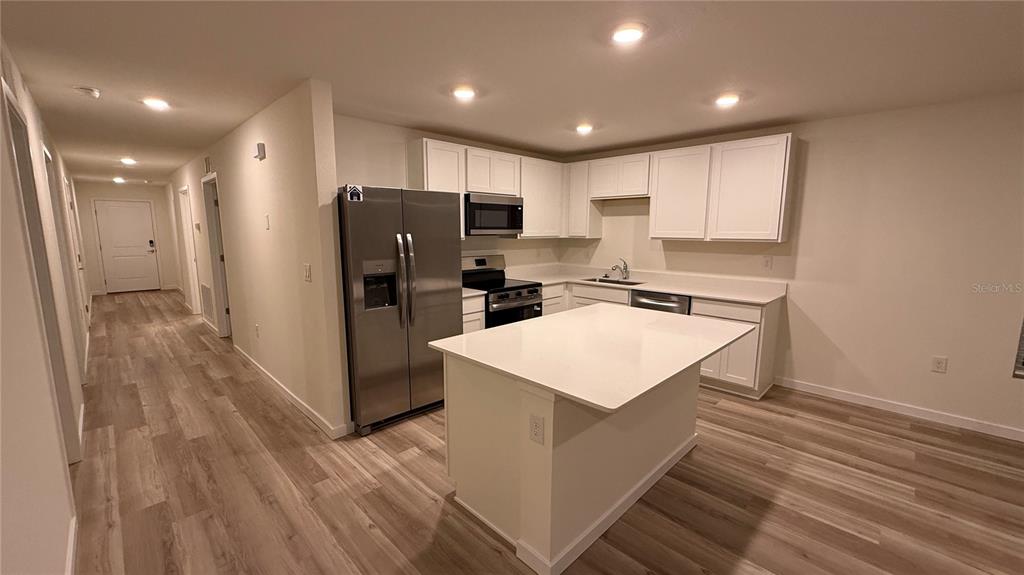 A kitchen with white cabinets, stainless steel appliances, and a central island with quartz countertops — 7749 SW 46TH COURT, OCALA, FL