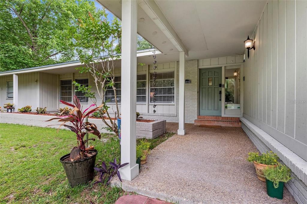 A covered concrete porch leads to a light green front door of a single-story house — 25446 SW 5 AVENUE, NEWBERRY, FL