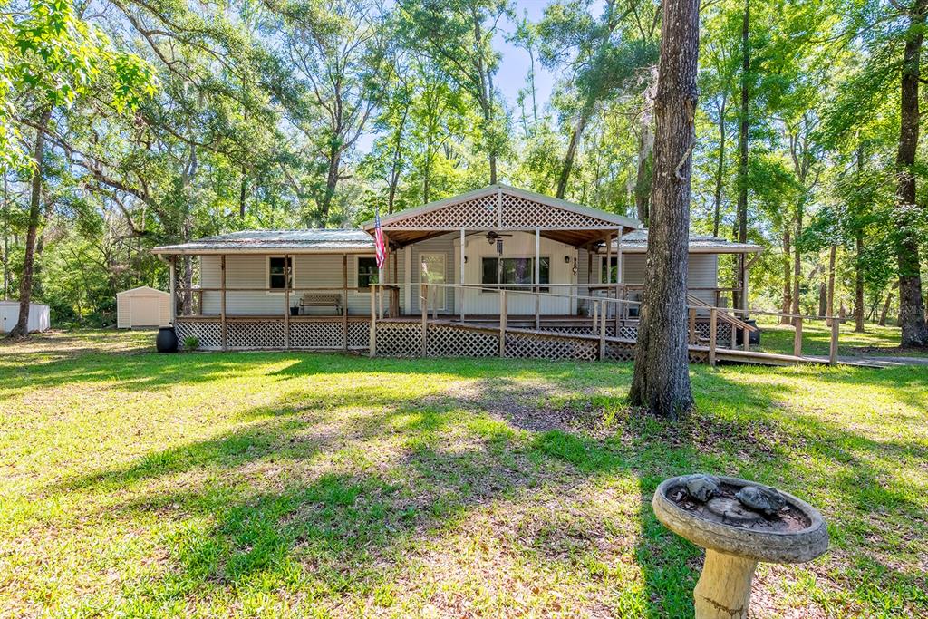 A single-story house with a large wooden deck and ramp sits in a wooded yard — 343 NE 743RD STREET, OLD TOWN, FL