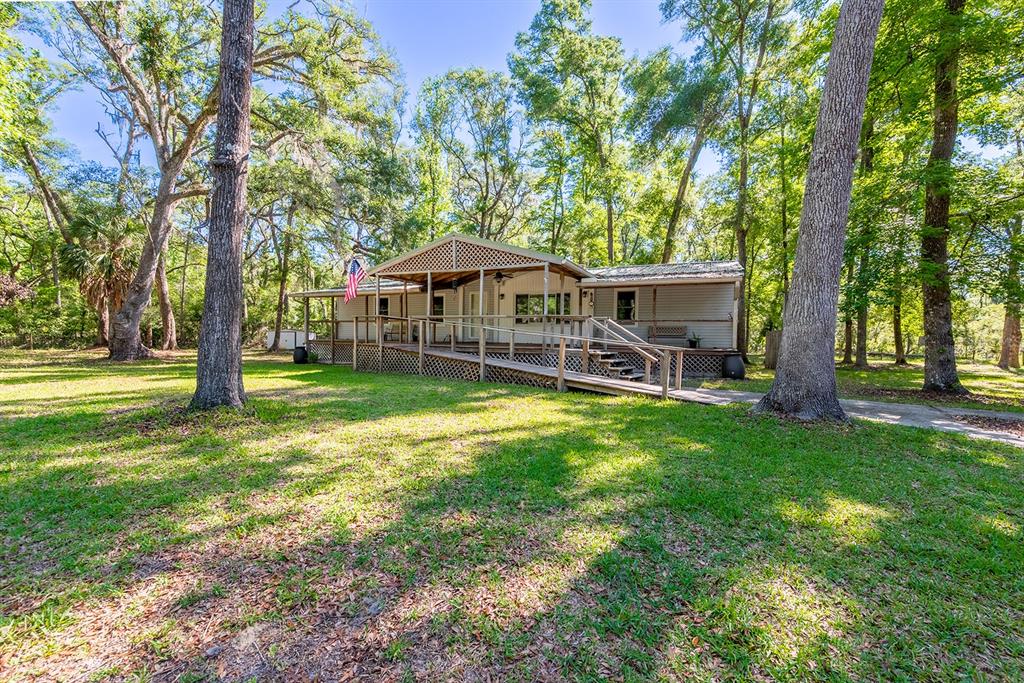 A single-story house with a wooden porch and wheelchair ramp sits in a wooded yard — 343 NE 743RD STREET, OLD TOWN, FL