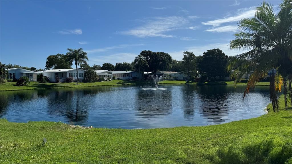 A pond with a fountain sits in front of several mobile homes under a blue sky — 1001 STARKEY ROAD UNIT 723, LARGO, FL
