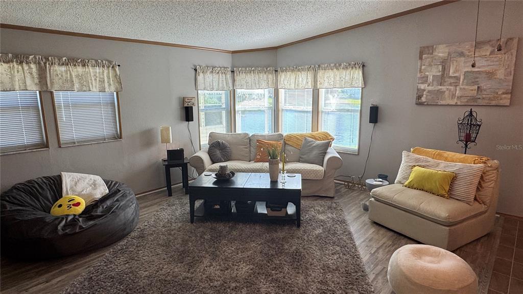 A living room features a sofa, beanbag chair, coffee table, and large windows with blinds — 1001 STARKEY ROAD UNIT 723, LARGO, FL