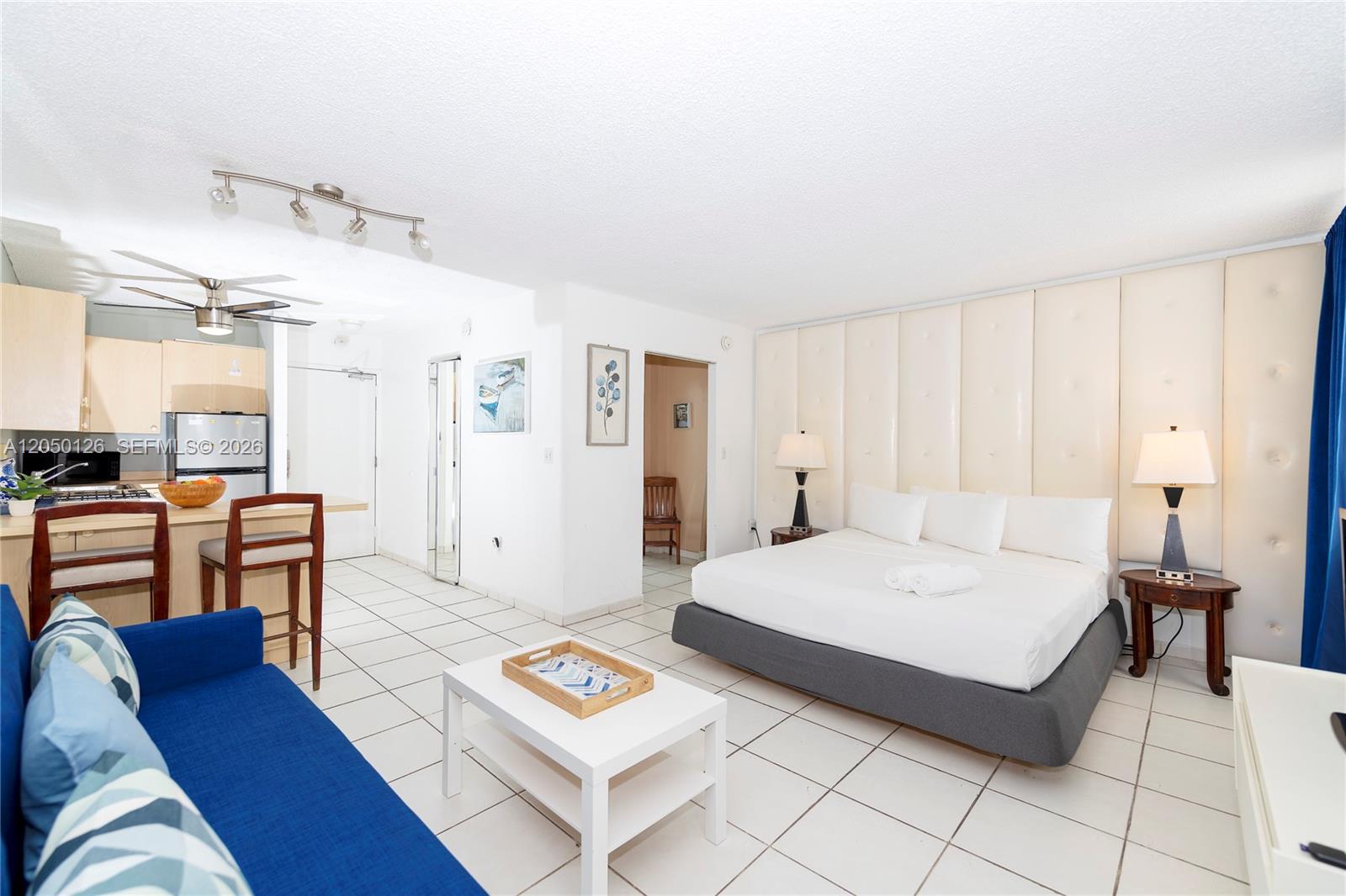This studio apartment features a kitchen, living area, and bed against a tufted headboard wall — 710 Washington Ave # 414, Miami Beach FL 33139, MIAMI BEACH, FL