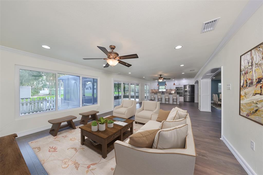 A bright, open-concept living room and kitchen area with dark wood floors and ceiling fans — 10922 PARK DRIVE, RIVERVIEW, FL