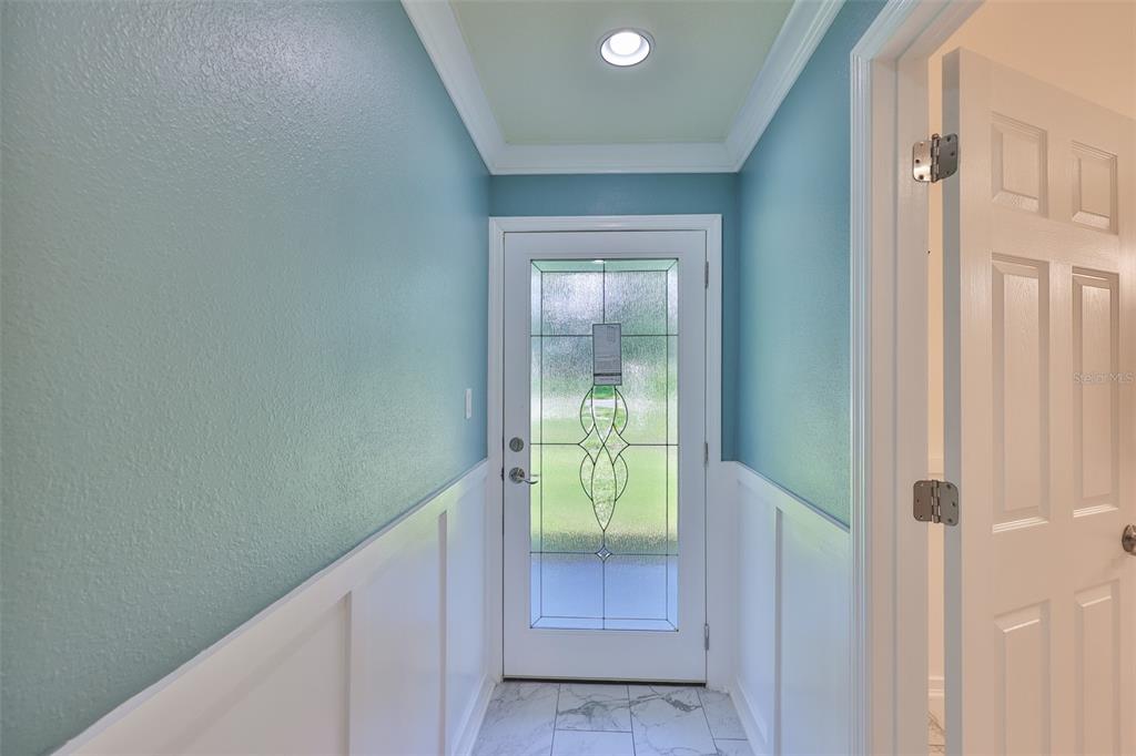 A bright entryway features blue walls, white wainscoting, a glass-paneled door, and marble-look tile flooring — 10922 PARK DRIVE, RIVERVIEW, FL