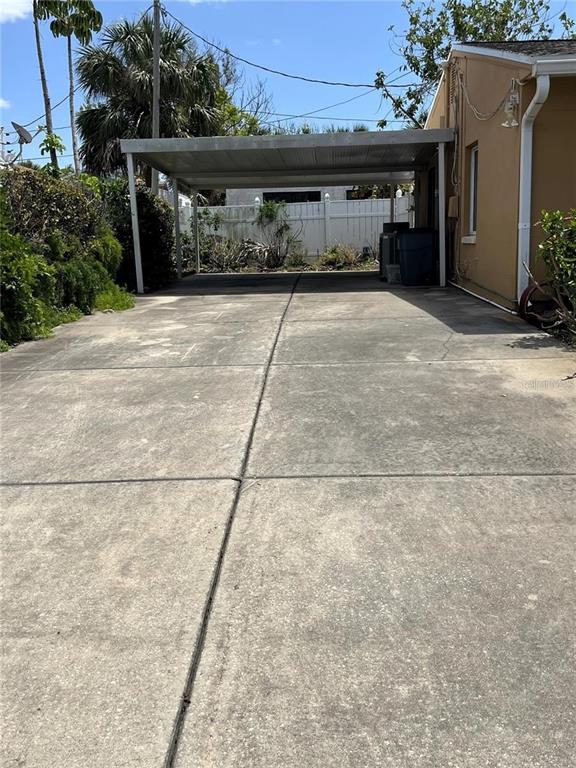 A concrete driveway leads to a covered carport beside a tan house — 360 72ND AVENUE, ST PETERSBURG, FL