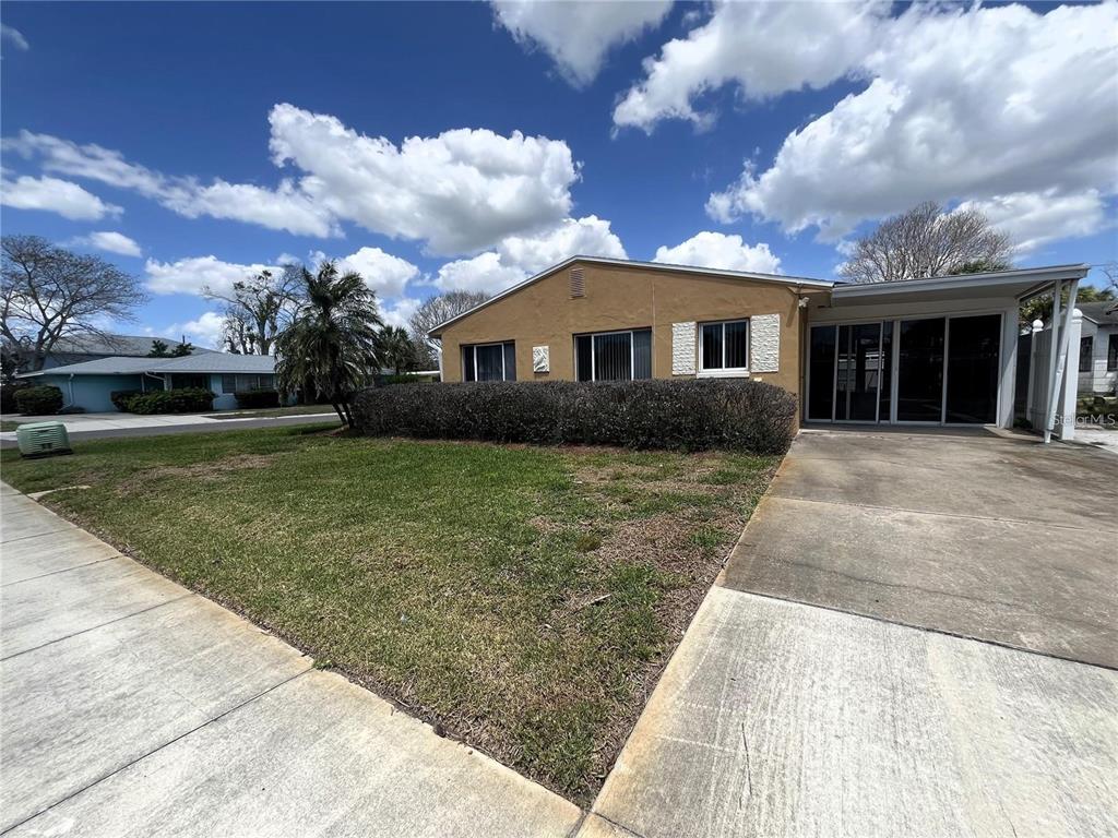 A tan, single-story house with a concrete driveway and a large hedge in the front yard — 360 72ND AVENUE, ST PETERSBURG, FL