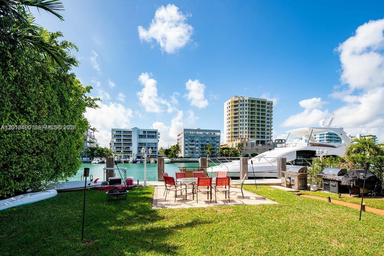 A backyard patio with outdoor furniture and a grill overlooks a canal with docked yachts — 34 Bal Bay Dr, Bal Harbour FL 33154, BAL HARBOUR, FL