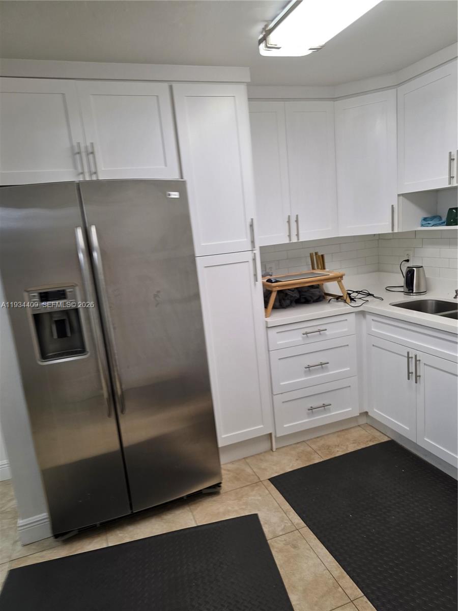 A kitchen features white cabinets, stainless steel appliances, and light-colored tile flooring — 1811 Jefferson St # 501, Hollywood FL 33020, HOLLYWOOD, FL