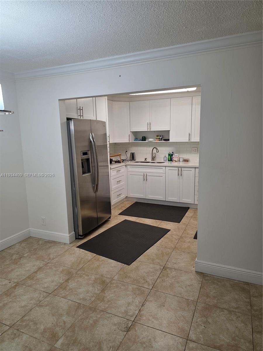 A kitchen features white cabinetry, stainless steel appliances, and light-colored tile flooring — 1811 Jefferson St # 501, Hollywood FL 33020, HOLLYWOOD, FL