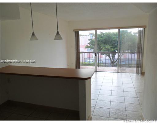 A kitchen breakfast bar overlooks a living area with tile floors and sliding glass doors — 10900 SW 104th St # 323, Miami FL 33176, MIAMI, FL