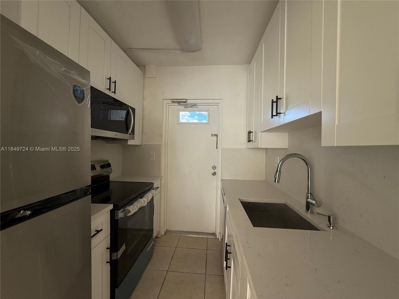 A galley kitchen features white cabinets, stainless steel appliances, and a light-colored countertop — 10900 SW 104th St # 323, Miami FL 33176, MIAMI, FL