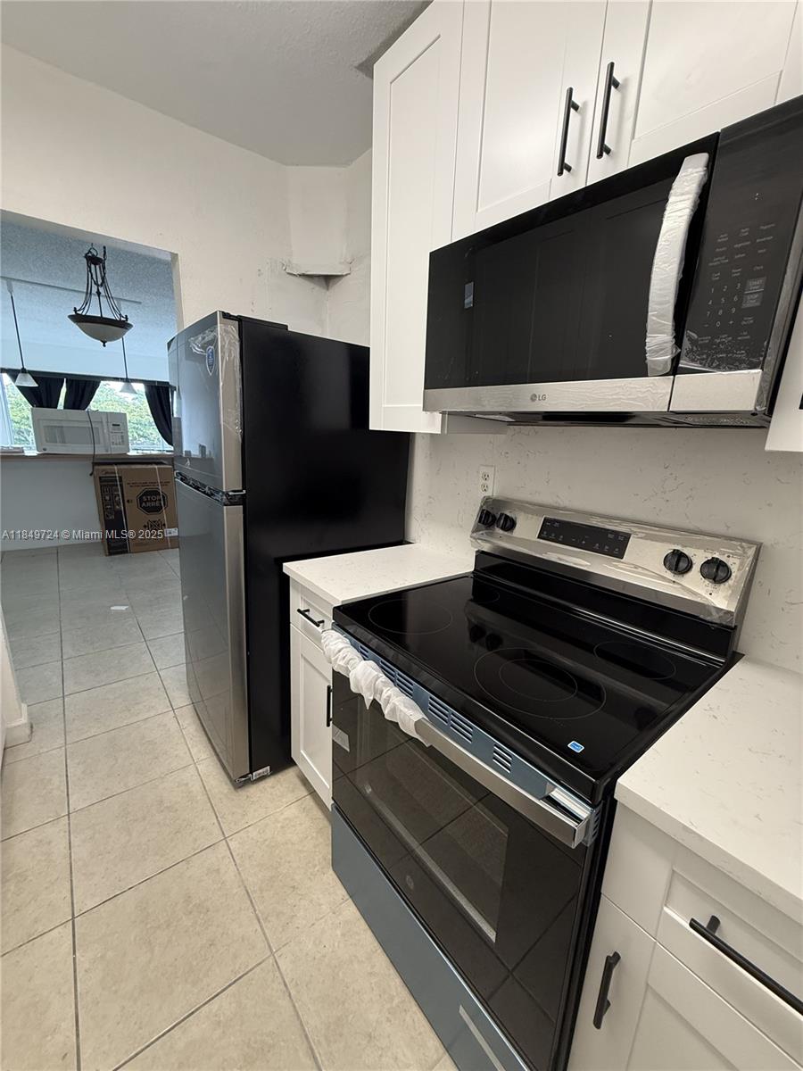 A kitchen features white cabinets, stainless steel appliances, and light-colored countertops — 10900 SW 104th St # 323, Miami FL 33176, MIAMI, FL