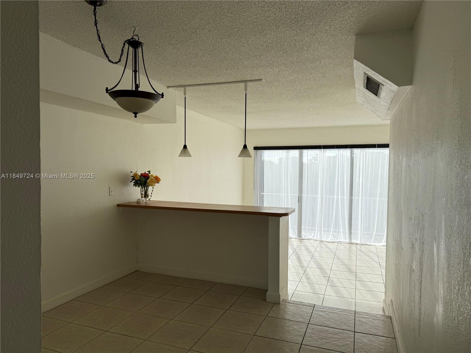 A dining area features a breakfast bar, pendant lighting, and tile flooring — 10900 SW 104th St # 323, Miami FL 33176, MIAMI, FL