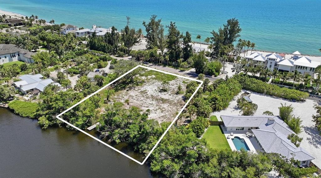 An aerial view shows a vacant rectangular lot situated between a house and a waterway — 7723 SANDERLING ROAD, SARASOTA, FL