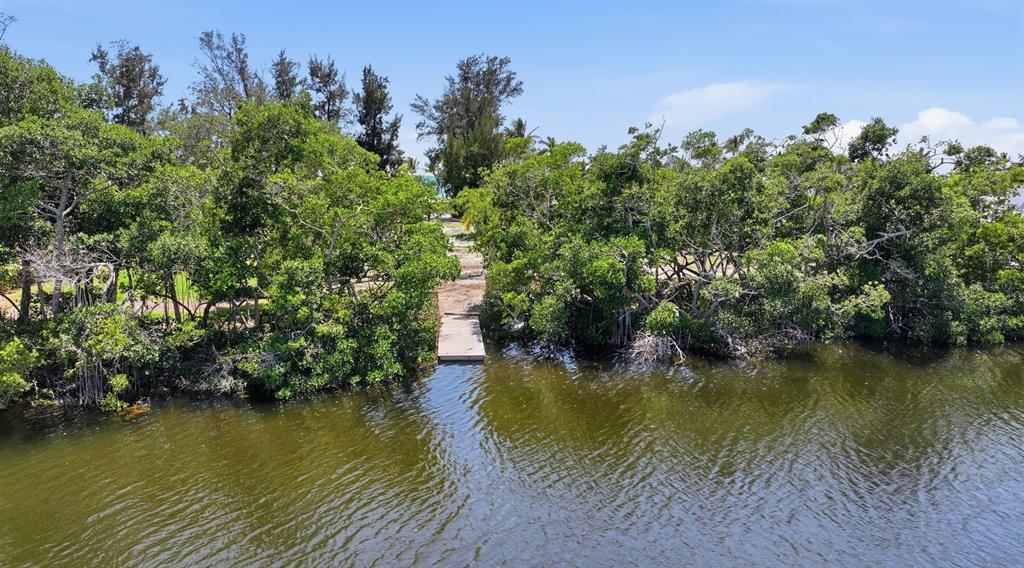 A small wooden dock extends from a wooded shoreline into a calm body of water — 7723 SANDERLING ROAD, SARASOTA, FL