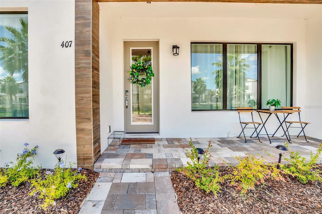 The exterior of a modern home features a paved porch, a front door, and windows — 407 VILLA DOMANI WAY, DAVENPORT, FL
