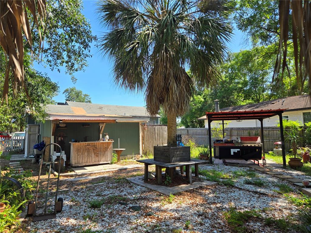 A backyard features a palm tree with a wooden bench, a bar, and a grill — 2010 W JEAN STREET, TAMPA, FL