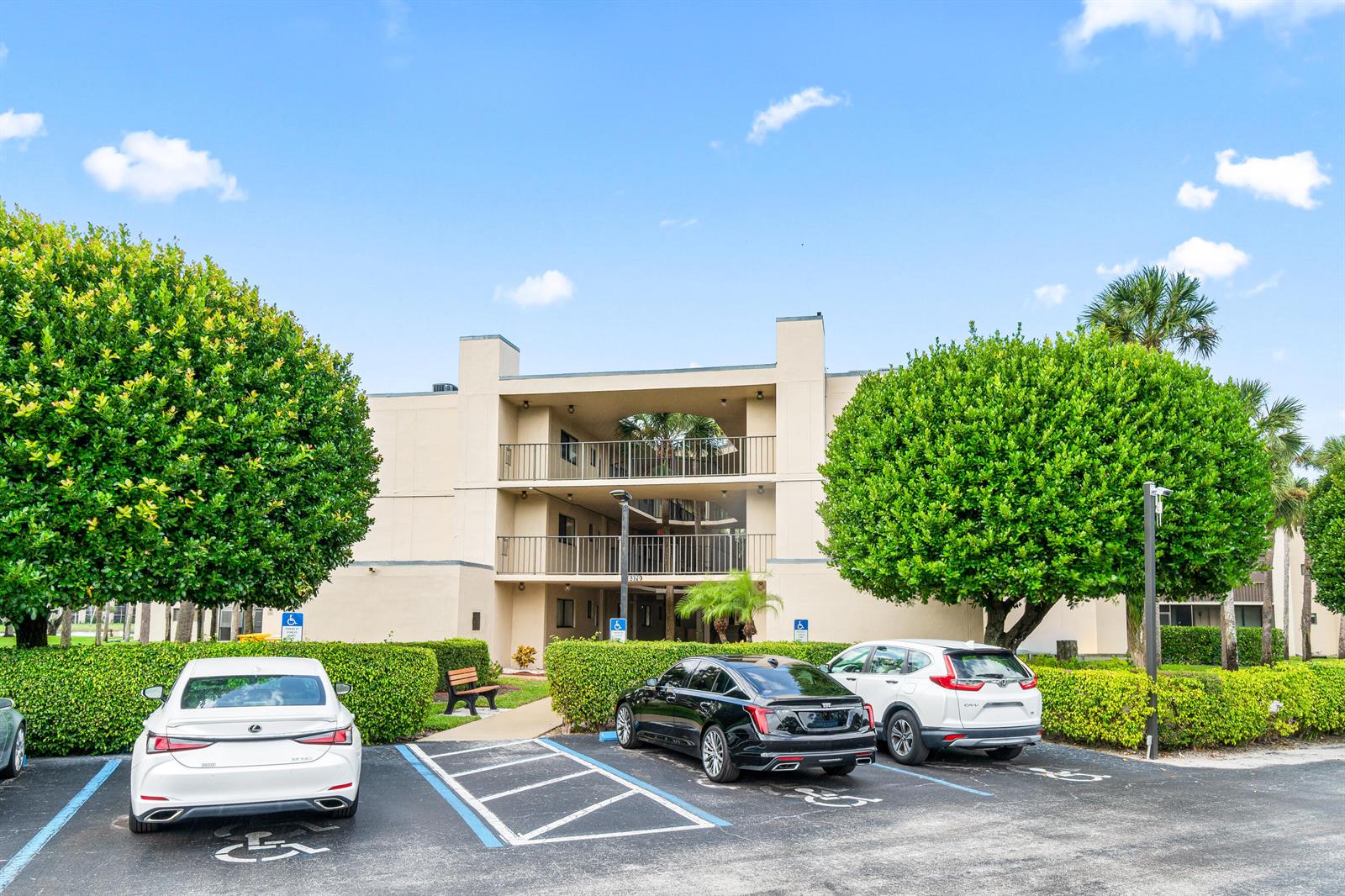 A three-story apartment building stands behind a parking lot with three parked cars — 5370 Las Verdes Circle # 209, Delray Beach FL 33484, DELRAY BEACH, FL
