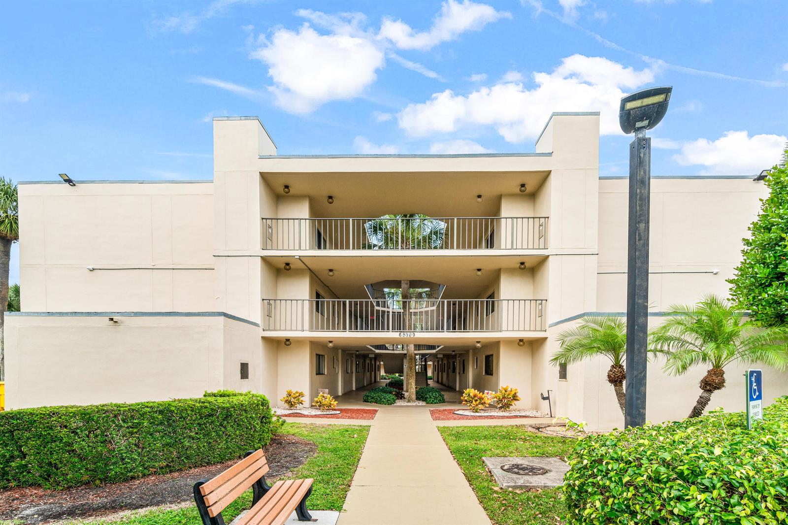A three-story apartment building exterior features a central walkway, balconies, and a landscaped front yard — 5370 Las Verdes Circle # 209, Delray Beach FL 33484, DELRAY BEACH, FL