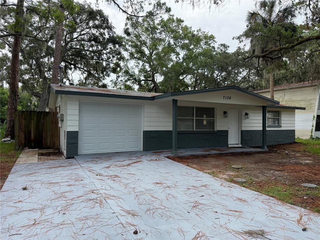A single-story house with white and dark gray exterior paint and a concrete driveway — 7138 PINEWOOD DRIVE, NEW PORT RICHEY, FL