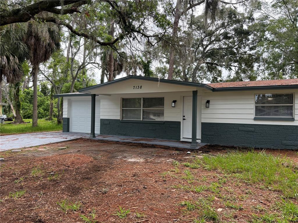 A single-story house with white and dark gray siding, a garage, and a front porch — 7138 PINEWOOD DRIVE, NEW PORT RICHEY, FL
