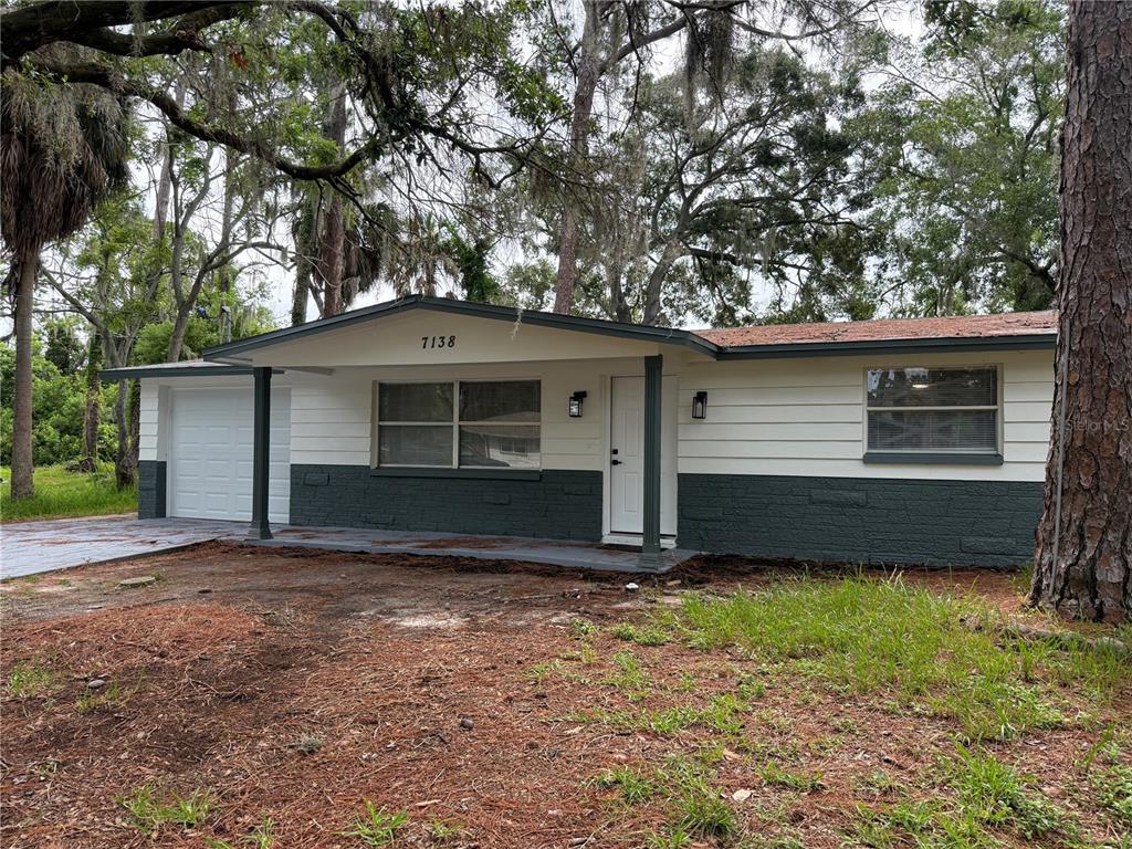 A single-story house with white siding, a dark gray brick base, and a covered porch — 7138 PINEWOOD DRIVE, NEW PORT RICHEY, FL