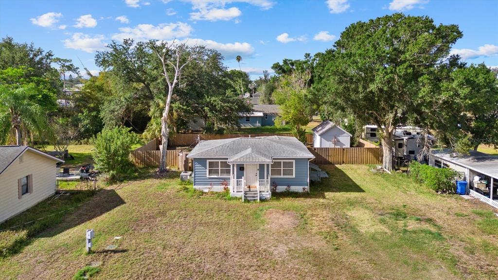 An exterior view of a blue single-story house with a front porch and large trees — 204 6TH AVENUE NW, RUSKIN, FL